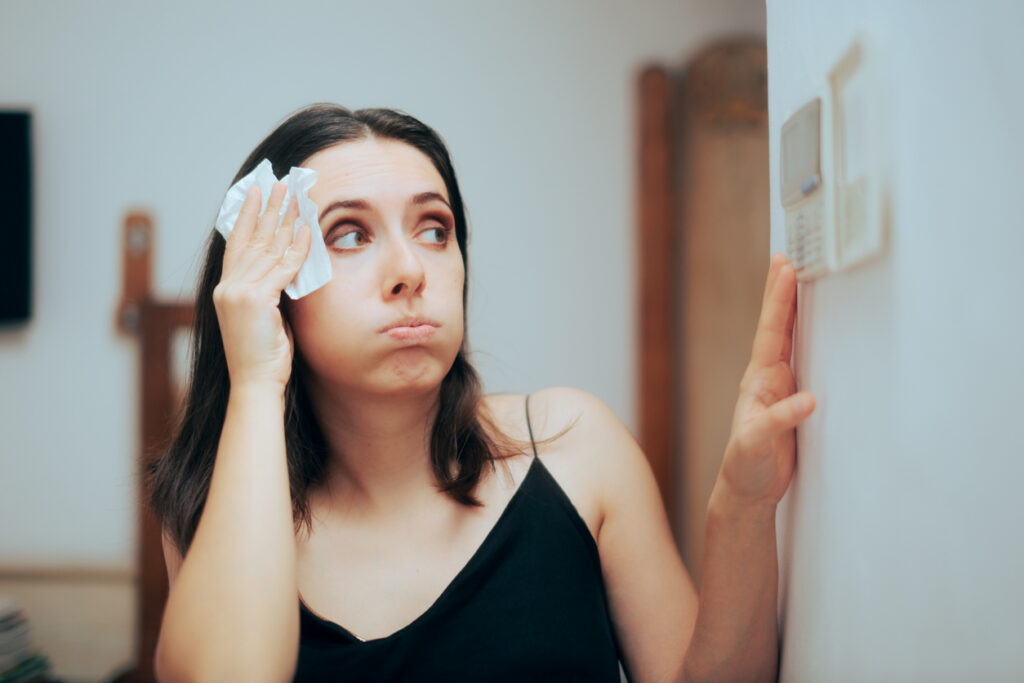 Woman adjusting AC temperature settings from feeling hot
