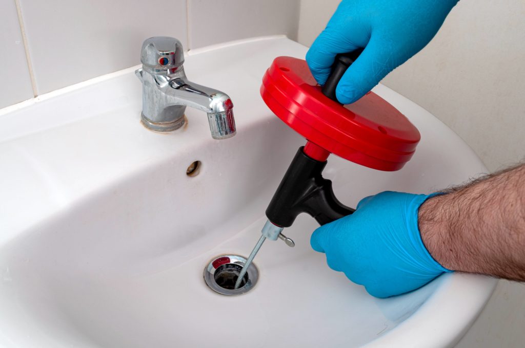 Plumber using a drain snake in a sink.